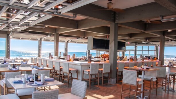 Un restaurante espacioso con techos altos, ventanas amplias y una zona de bar.