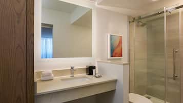 A bathroom with a large mirror, a sink, a toilet, and a shower area.