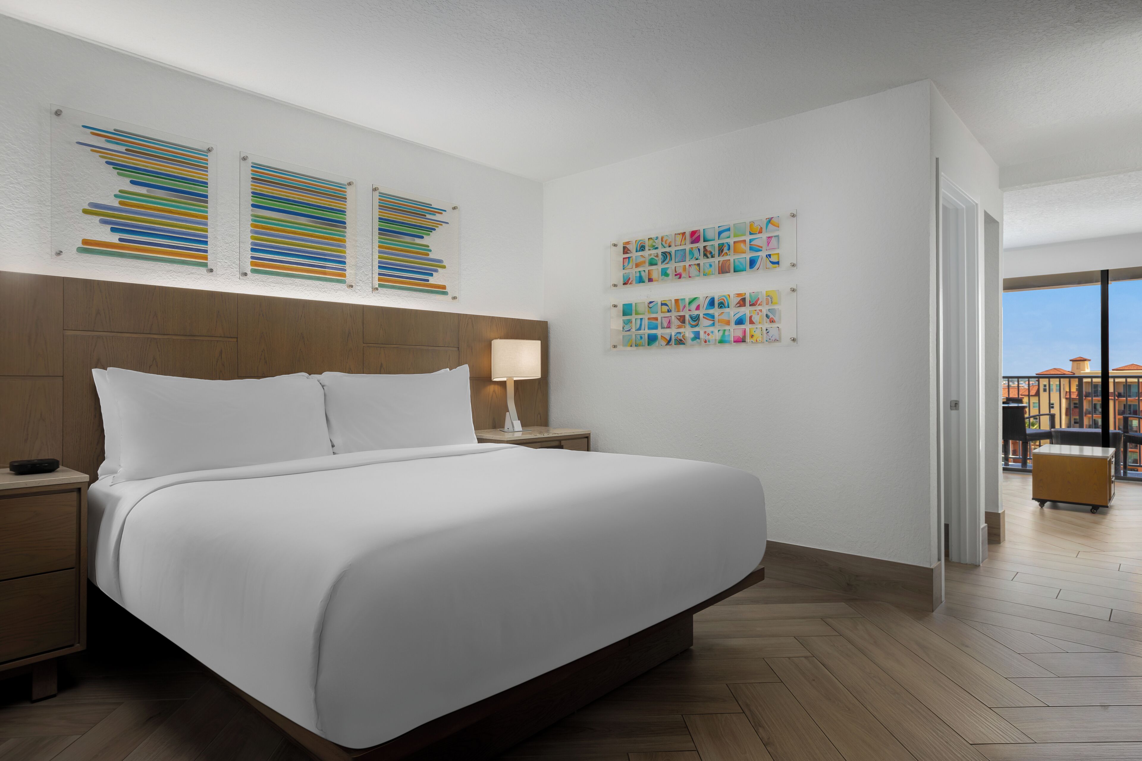 Ein Hotelzimmer mit einem großen Bett, einem Holz-Kopfteil, einem Nachttisch, einer Nachttischlampe und Bildern an den Wänden.