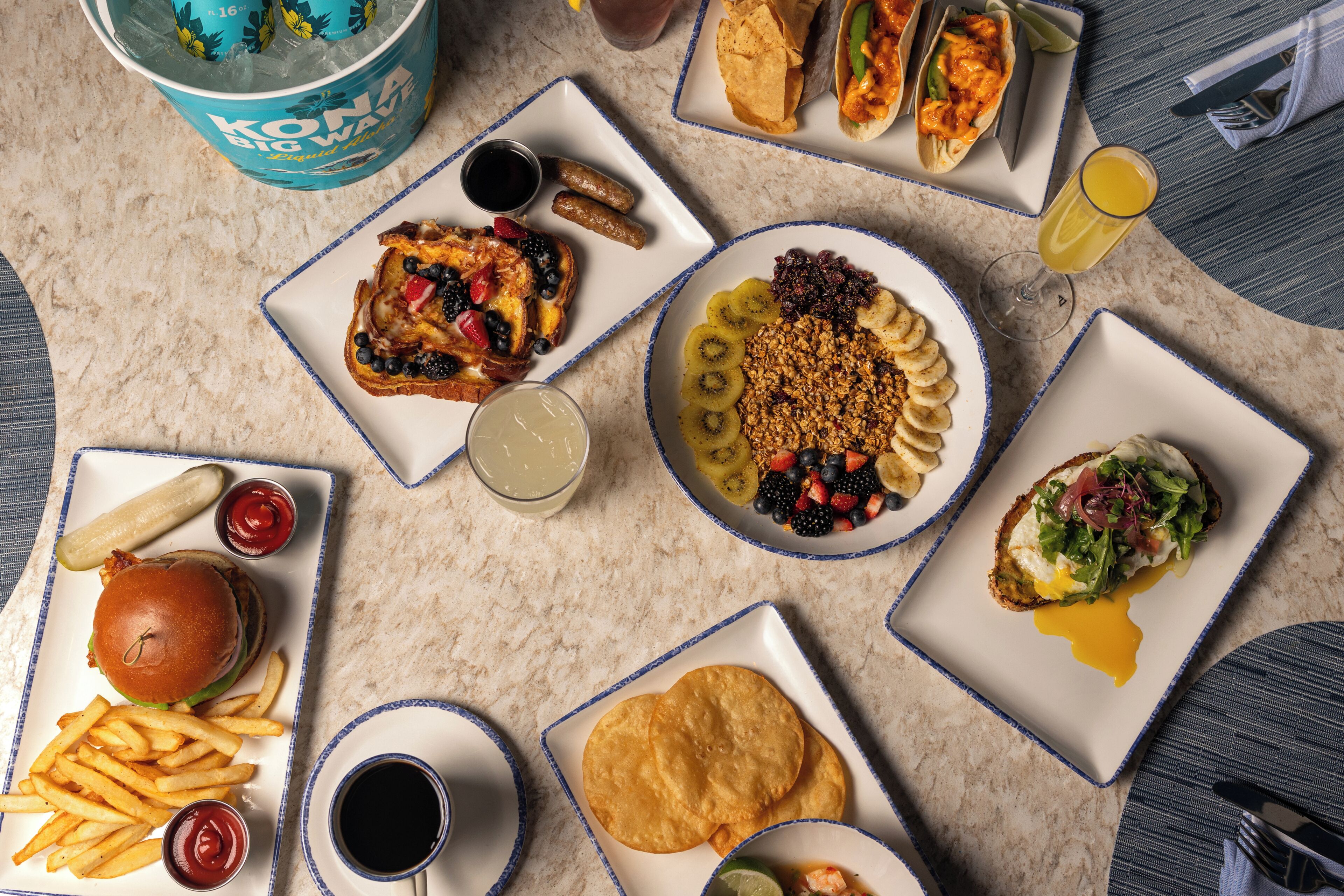 A variety of food items on plates, including tacos, a burger, and a sandwich.