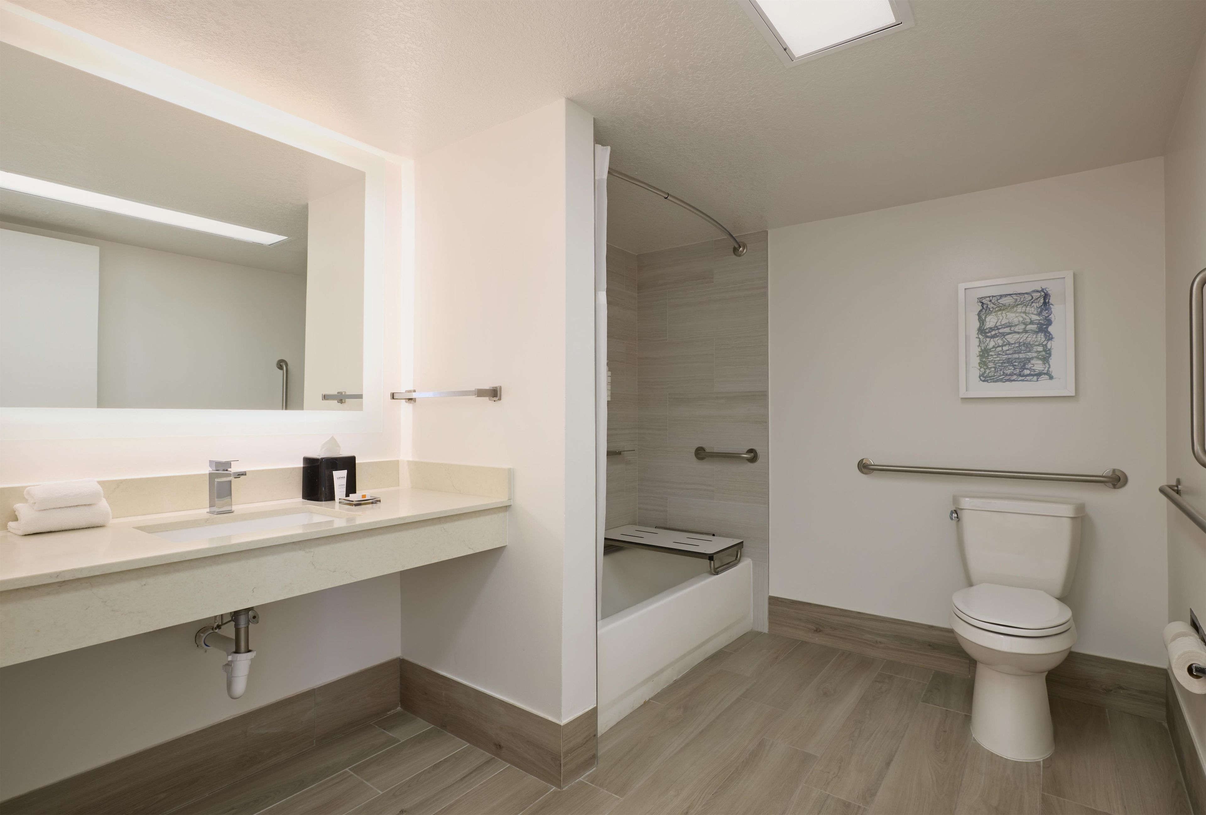 Een moderne badkamer met een grote spiegel, een wastafel met een handdoek, een toilet en een douchehoek.