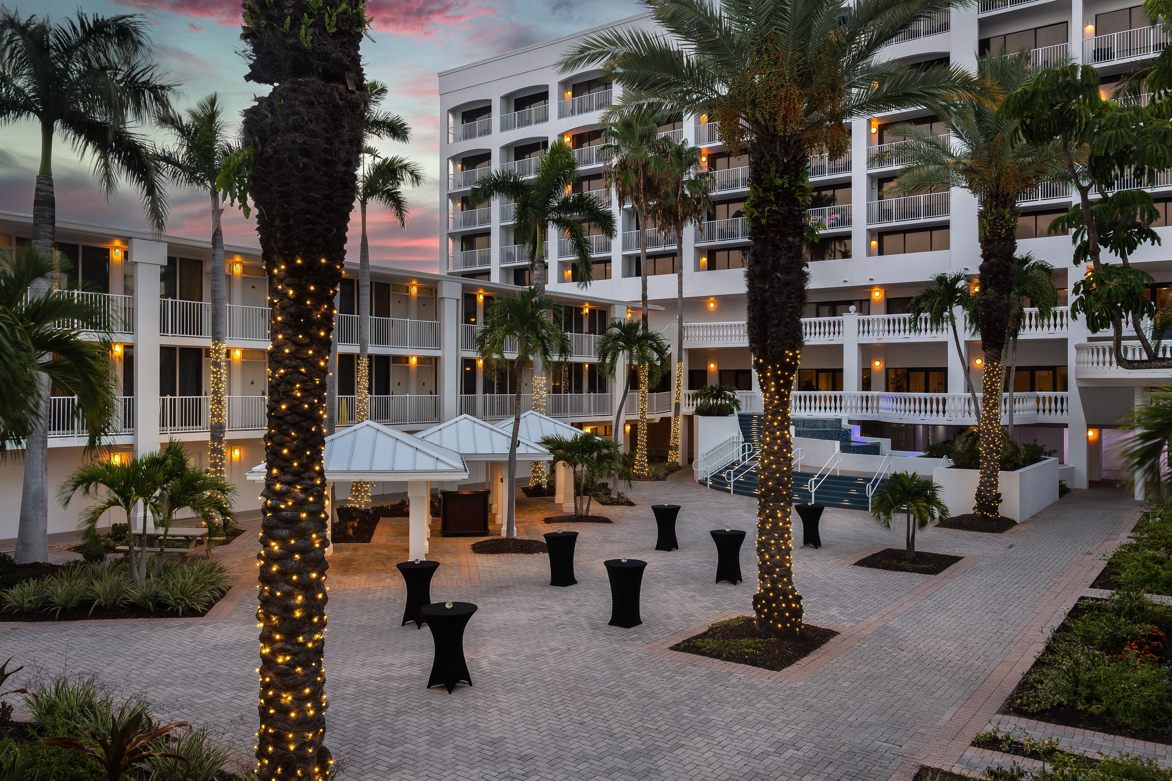 Cortile di un hotel con palme, posti a sedere all'aperto e area piscina.