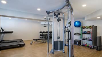 Ein Fitnessstudio mit Laufband, Kraftgeräten, Kettlebells und Trainingsbällen.
