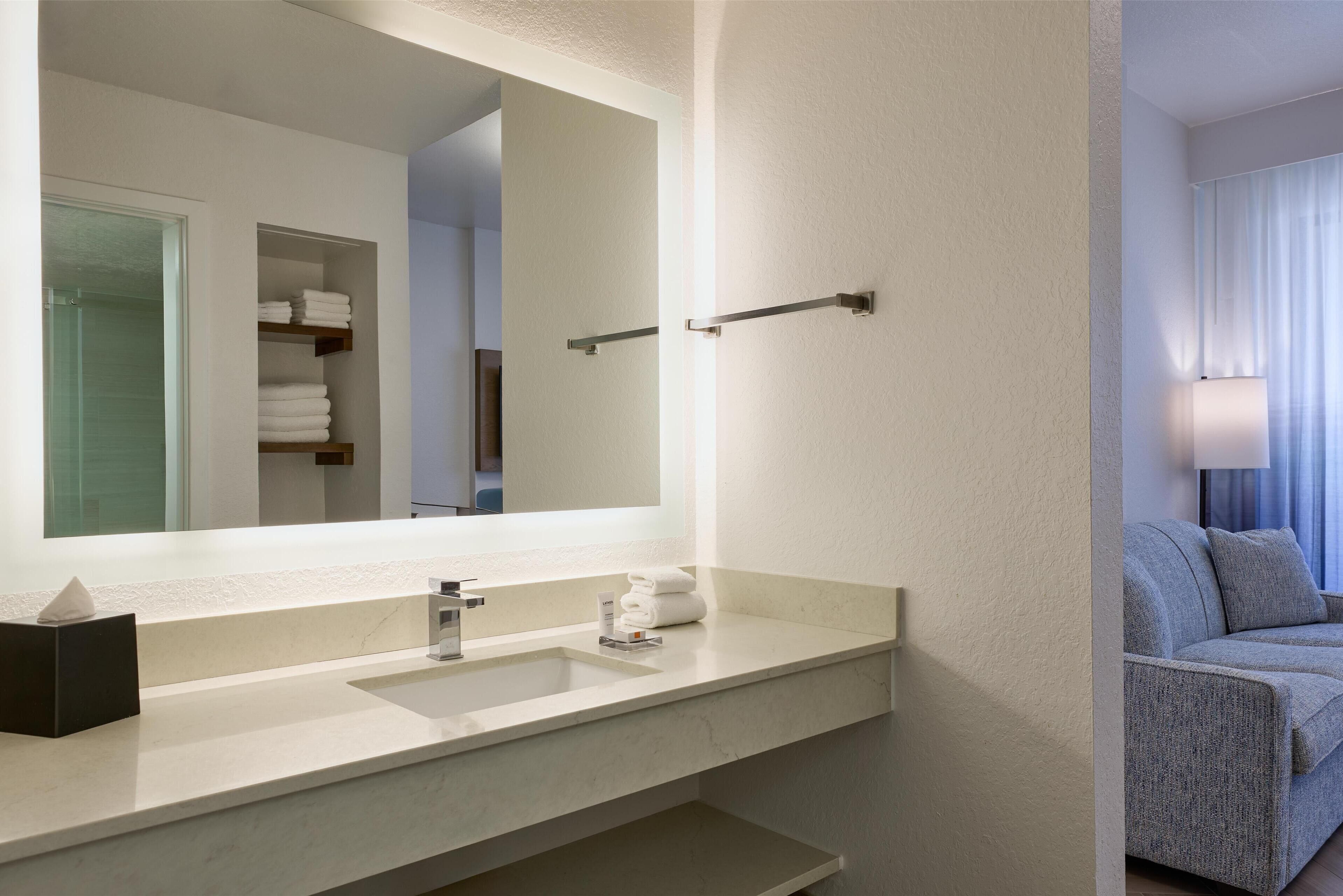 A modern bathroom with a large mirror, a sink, and a towel rack.