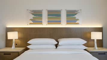 Una cama bien arreglada con sábanas blancas, dos mesitas de noche con lámparas y un cabecero de madera.