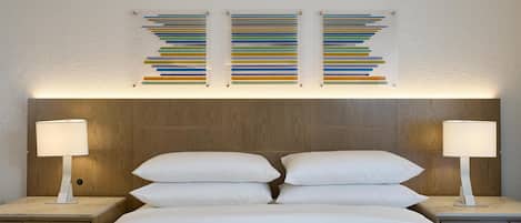 Una cama bien arreglada con sábanas blancas, dos mesitas de noche con lámparas y un cabecero de madera.