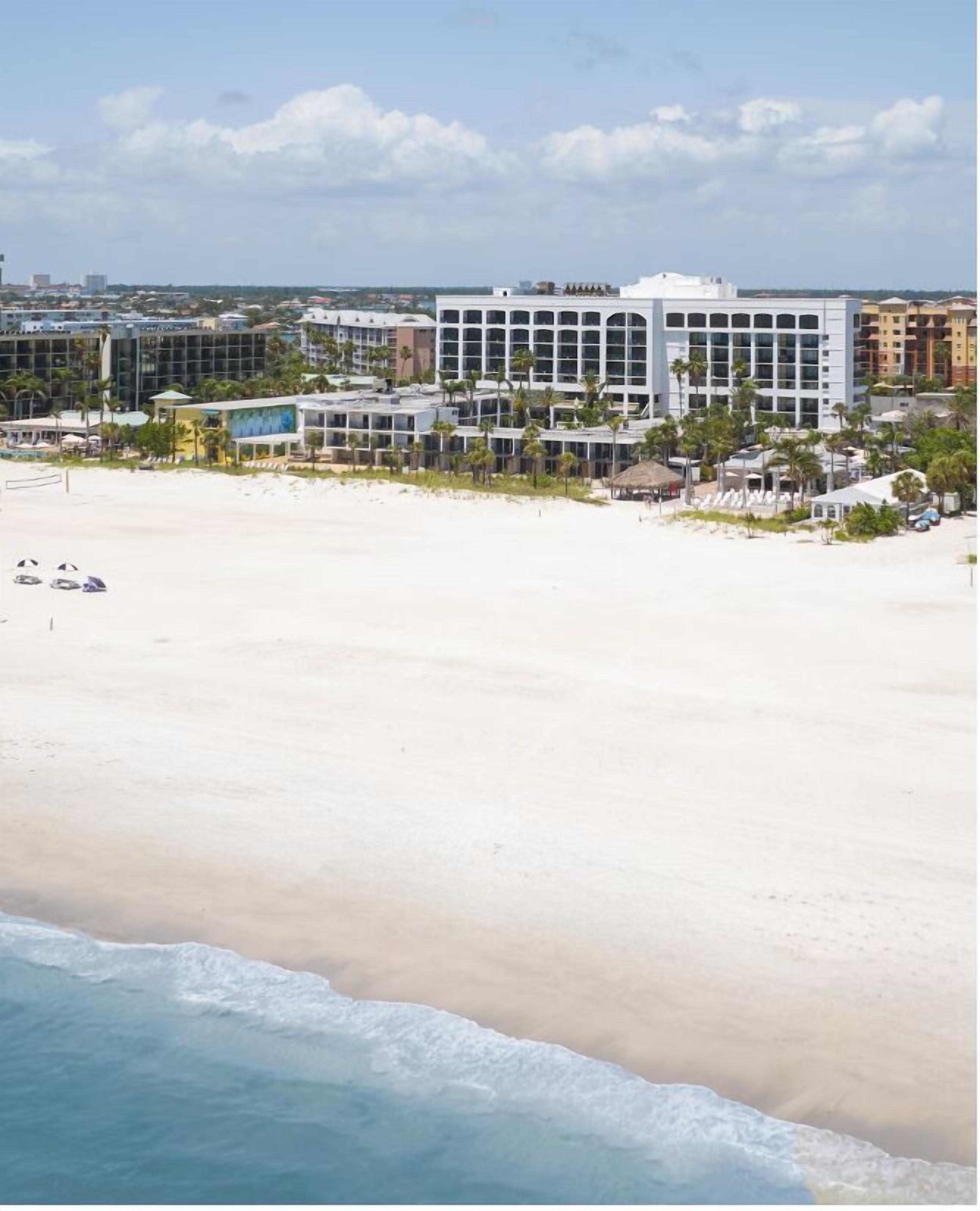 A beachfront hotel with a large building, a sandy beach, and the ocean.
