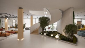 A modern interior with a curved staircase, seating areas, and indoor plants.