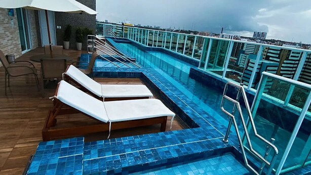 A rooftop pool area with lounge chairs and a glass railing. - Edificio Promenade II - Apto 1101 (Maceió)
