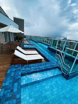 A rooftop pool area with lounge chairs and a glass railing. - Edificio Promenade II - Apto 1101 (Maceió)
