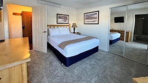 A hotel room with a bed, a desk, a lamp, and a TV. - Unit 114 - Updated Condo (Winter Park)