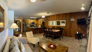 A cozy living room with a sofa, a coffee table, and a dining area with chairs and a table. - Unit 212 - Standard Condo (Winter Park)