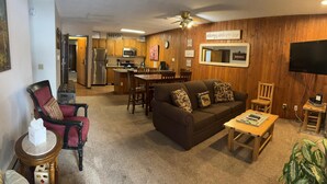 A cozy living room with a sofa, armchair, and coffee table, a kitchen with wooden cabinets, and a dining area. - Unit 512 - Updated Condo (Winter Park)