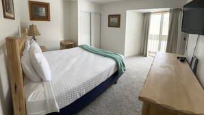 Ein Schlafzimmer mit einem Bett, einem Schreibtisch, einem Stuhl, einer Lampe und einem Fernseher.