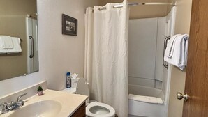 Et badeværelse med vask, toilet og bruser.