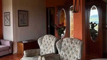 Quarto com duas poltronas estofadas, um armário de madeira e um espelho grande.