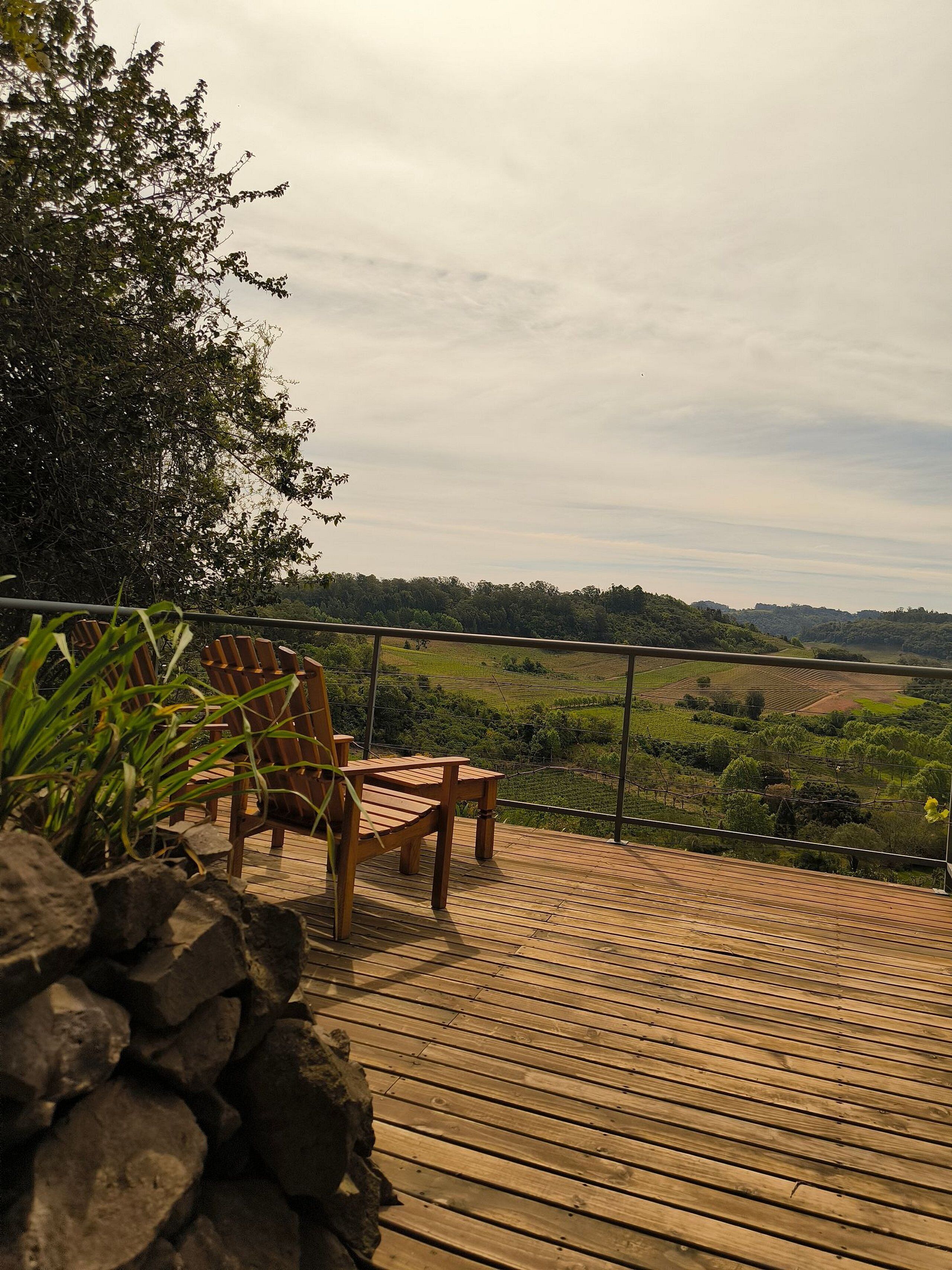 A wooden deck with chairs overlooking a lush green landscape.