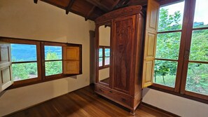 A room with wooden floors, a large wooden wardrobe, and two windows with wooden frames. - Pousada Borghetto (Bento Gonçalves)
