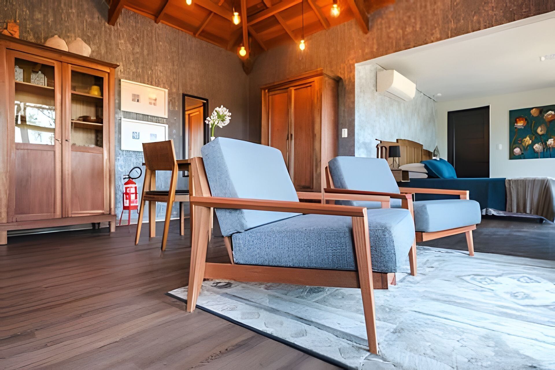 Una sala de estar moderna con muebles de madera, un comedor y una cocina visibles a través de un umbral abierto.