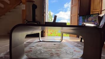 Una sala de estar moderna con un ventanal grande, un sofá, un televisor y una escalera.