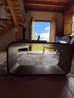 Una sala de estar moderna con un ventanal grande, un sofá, un televisor y una escalera.