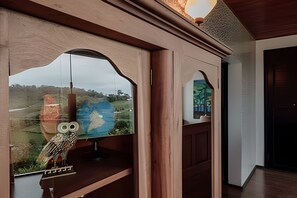 Quarto com uma janela grande, adornado com uma coruja decorativa e um globo.