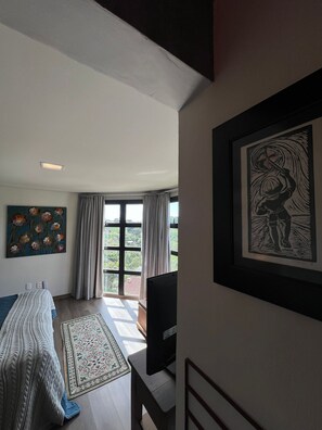 A bedroom with a bed, a TV, a window with curtains, and a painting on the wall. - Pousada Borghetto (Bento Gonçalves)