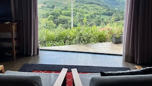 A room with a large window offering a view of a green landscape and hills. - Pousada Borghetto (Bento Gonçalves)