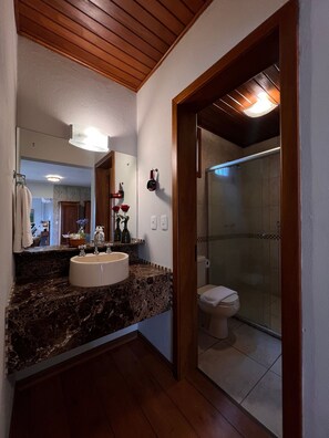 A bathroom with a marble sink, a mirror, a shower, and a wooden ceiling. - Pousada Borghetto (Bento Gonçalves)
