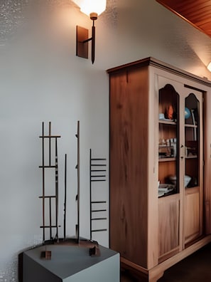 A room with a wooden cabinet, a wall-mounted light fixture, and a small table with a few items on it. - Pousada Borghetto (Bento Gonçalves)