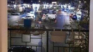 Uitzicht vanaf een balkon 's nachts op een straat met auto's en gebouwen.