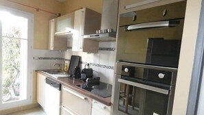 Een keuken met een vaatwasser, dubbele oven en een raam met uitzicht op groen.