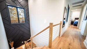 A staircase with wooden railings and a black wall with a geometric pattern. - Welcome to PEDAL AND PLUNGE (Bella Vista)