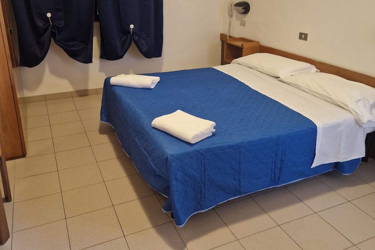 A hotel room with a bed, a telephone, and curtains.