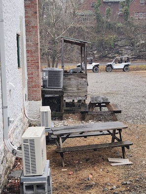 Un edificio con muros de ladrillo y estructura de madera, con una mesa y bancos.