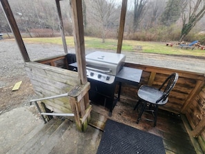 An outdoor kitchen area with a grill, a table, and a chair.