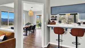 Une cuisine moderne avec un coin bar, de grandes fenêtres et un espace repas offrant une vue agréable.