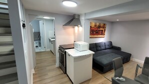 A compact living space with a kitchenette, a sofa, and a dining area. - A Basement Studio for 2 (Brampton)