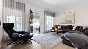 A modern living room with a black leather chair, a grey sofa, and a wooden coffee table. - Fox on Church - pet friendly 2 bedroom home (Hepburn Springs)