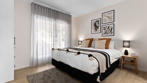 A modern bedroom with a large bed, a wooden nightstand, and a window with sheer curtains. - Fox on Church - pet friendly 2 bedroom home (Hepburn Springs)