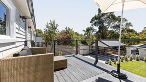 A wooden deck with wicker furniture and a large umbrella. - Fox on Church - pet friendly 2 bedroom home (Hepburn Springs)