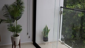 Ein Balkon mit einem Blumentopf, einer kleinen Pflanze und Blick auf grüne Vegetation.