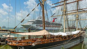A large sailing ship docked at a marina with a modern cruise ship in the background. - Ocean & Pool View Top Floor | 2 Pools| HotTub |GYM (Galveston)