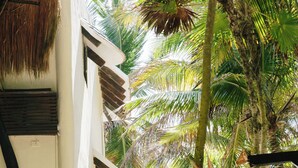 A white building with a thatched roof, surrounded by palm trees. - Olas Tulum (Tulum)