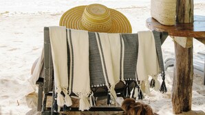 A beach umbrella, a woven basket, and a beach chair with a blanket. - Olas Tulum (Tulum)