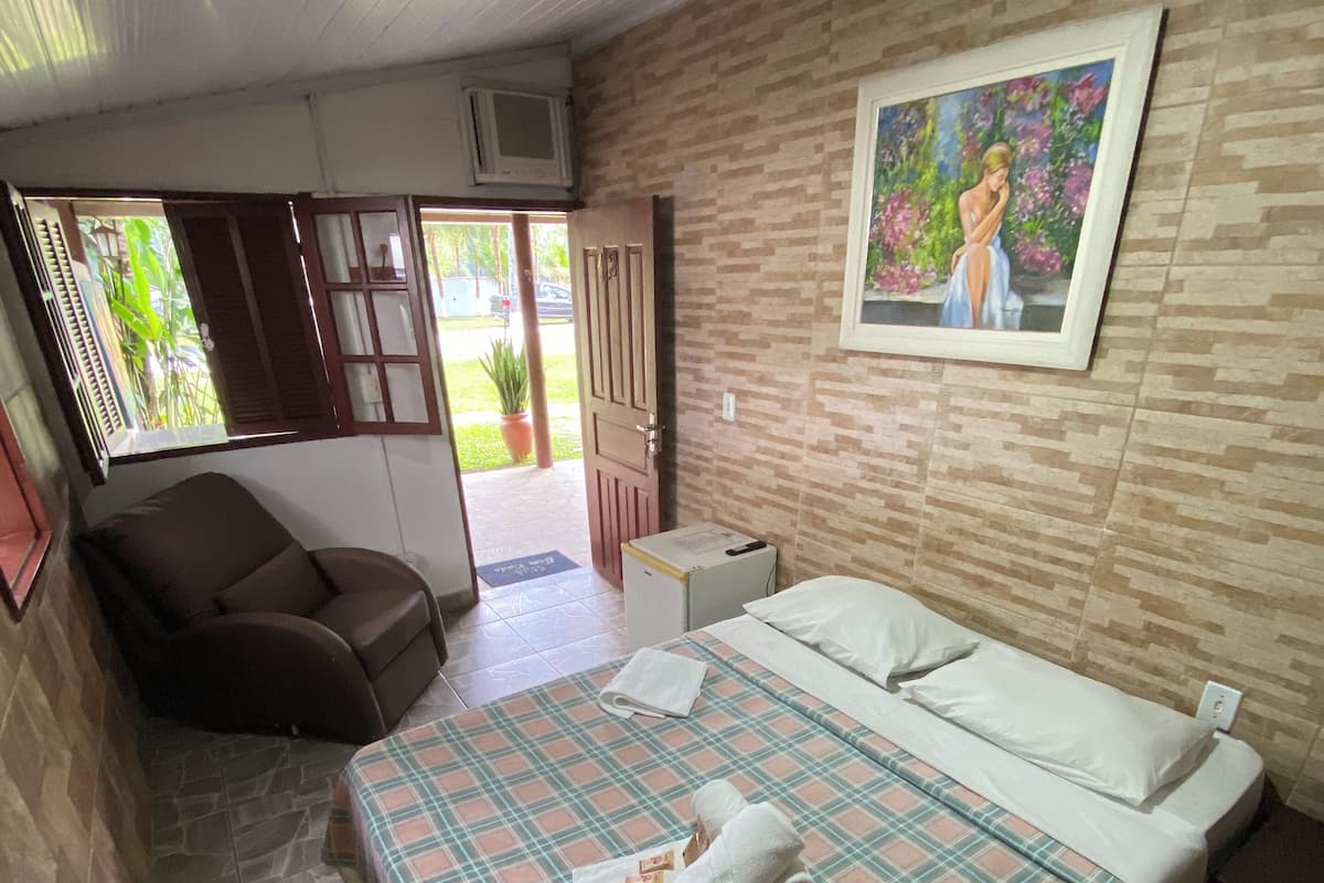 Ein Hotelzimmer mit Bett, Sessel, kleinem Tisch und einem Bild an der Wand.