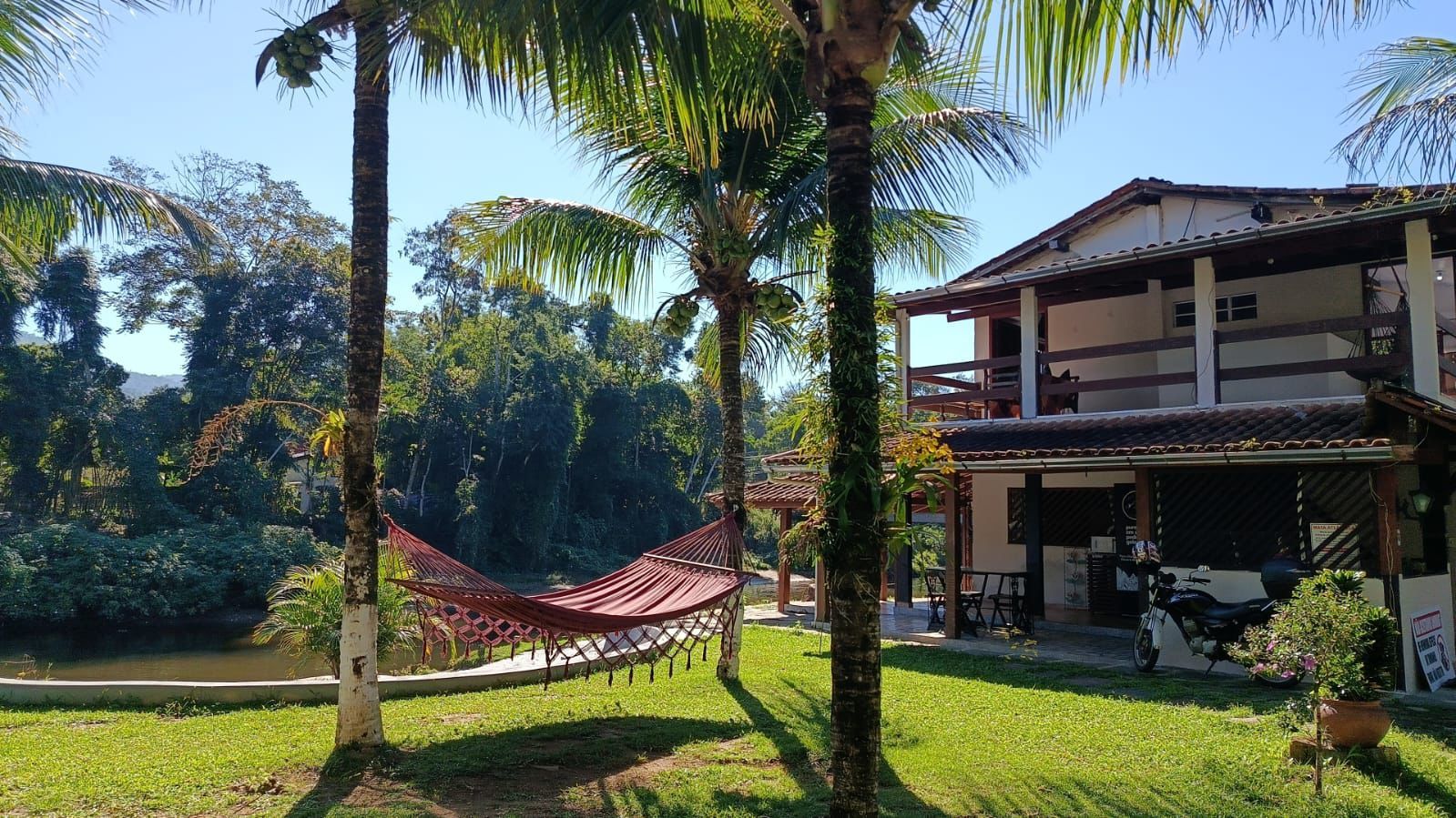 A house with a covered porch, a hammock, and a motorcycle parked outside.
