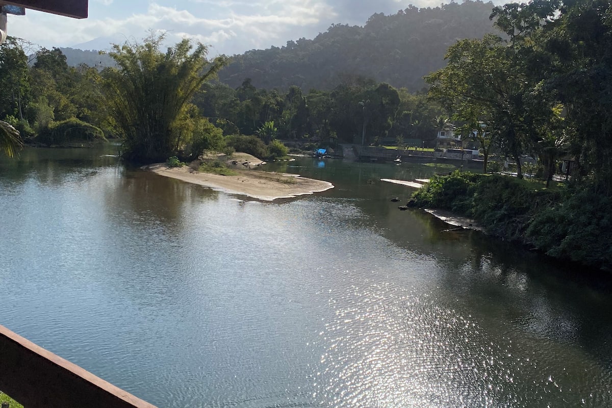 Blick auf einen Fluss von einer überdachten Terrasse mit Holzdeck.