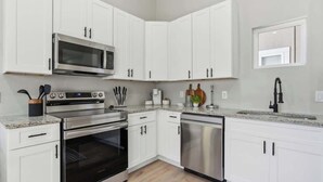 Cocina moderna con armarios blancos, electrodomésticos de acero inoxidable y encimera de granito.