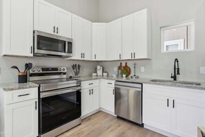 A modern kitchen with white cabinets, stainless steel appliances, and a granite countertop.